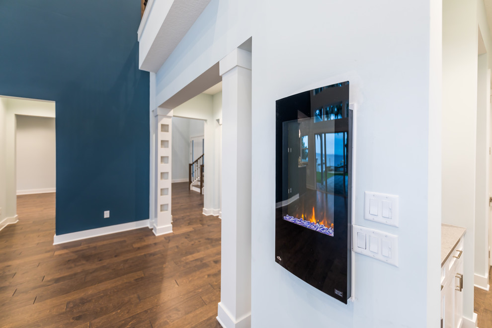 ジャクソンビルにある高級な広い地中海スタイルのおしゃれなオープンリビング (青い壁、無垢フローリング、吊り下げ式暖炉、ホームバー、壁掛け型テレビ、マルチカラーの床) の写真