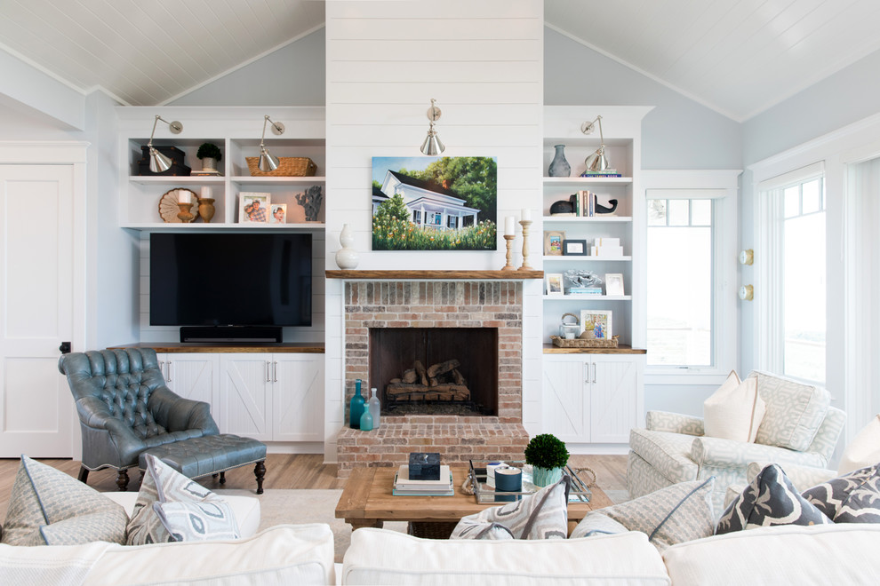 Cette image montre une salle de séjour marine ouverte avec un mur bleu, parquet clair, une cheminée standard, un manteau de cheminée en brique et un téléviseur encastré.
