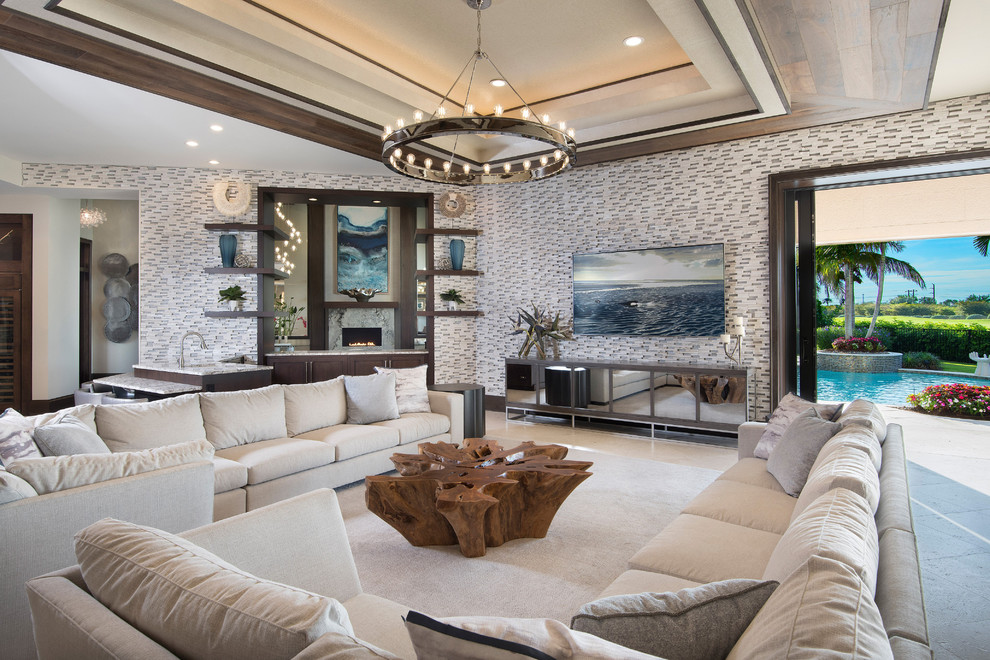 Large transitional open concept marble floor and beige floor family room photo in Miami with a bar, multicolored walls, a standard fireplace, a stone fireplace and a wall-mounted tv