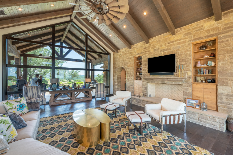 Family room - large cottage open concept dark wood floor and brown floor family room idea in Austin with beige walls, a standard fireplace, a stone fireplace and a wall-mounted tv