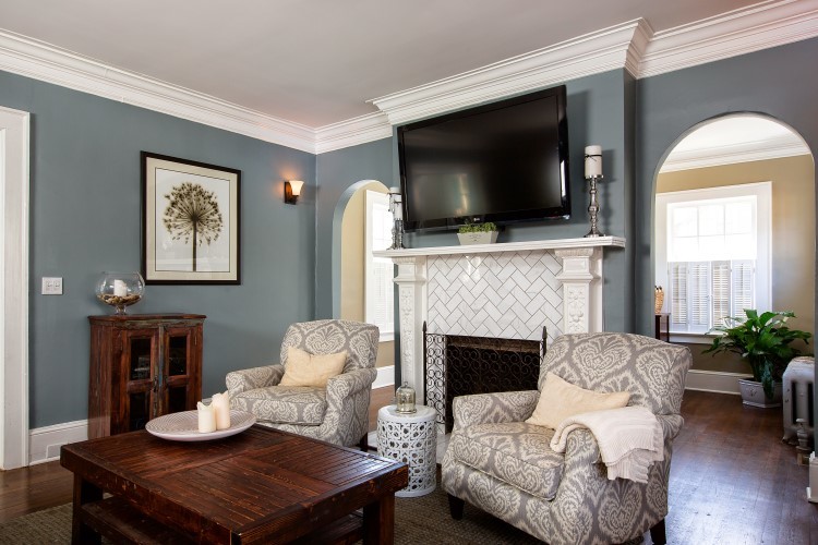 Modelo de sala de estar abierta clásica renovada de tamaño medio con suelo de madera en tonos medios, todas las chimeneas, marco de chimenea de baldosas y/o azulejos, televisor colgado en la pared y paredes grises