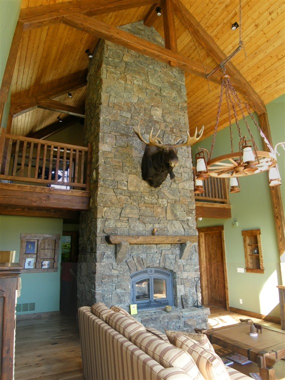 Exempel på ett mellanstort rustikt allrum på loftet, med mellanmörkt trägolv, en standard öppen spis, en spiselkrans i sten och gröna väggar