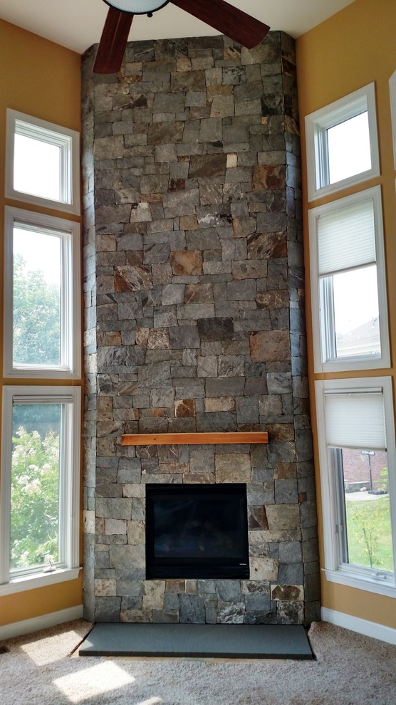 Imagen de sala de estar actual con chimenea de esquina y marco de chimenea de piedra