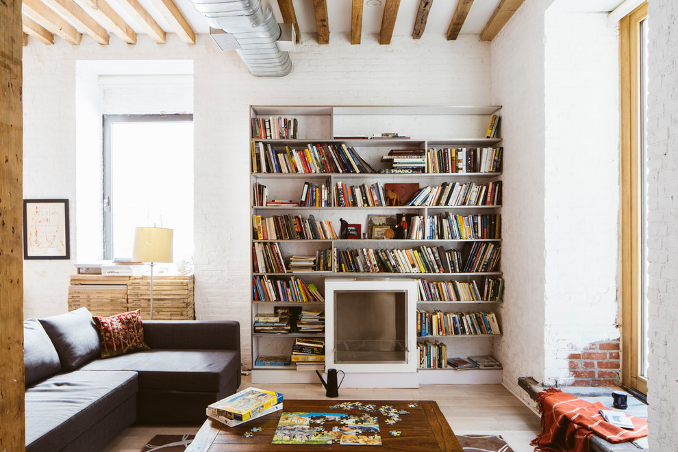 Foto di un soggiorno industriale di medie dimensioni con libreria, pareti bianche, parquet chiaro, camino classico e nessuna TV