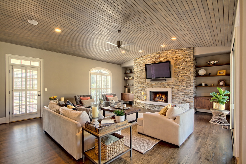 Farmhouse living room in Atlanta with grey walls, medium hardwood flooring, no fireplace, a wall mounted tv and a stone fireplace surround.