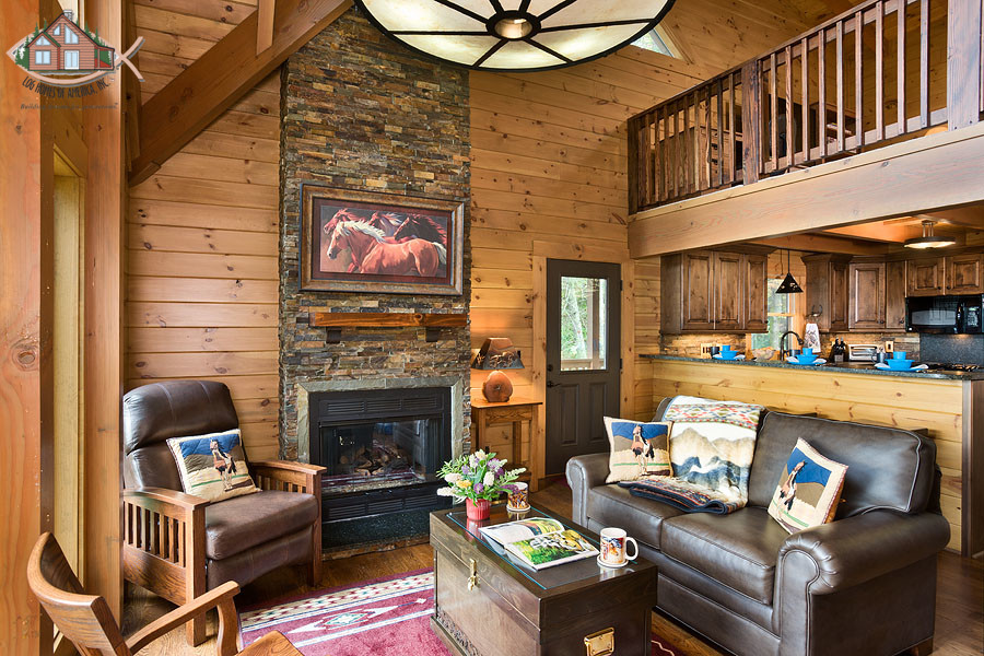 Ejemplo de sala de estar tipo loft rural de tamaño medio sin televisor con paredes marrones, suelo de madera en tonos medios, todas las chimeneas y marco de chimenea de piedra