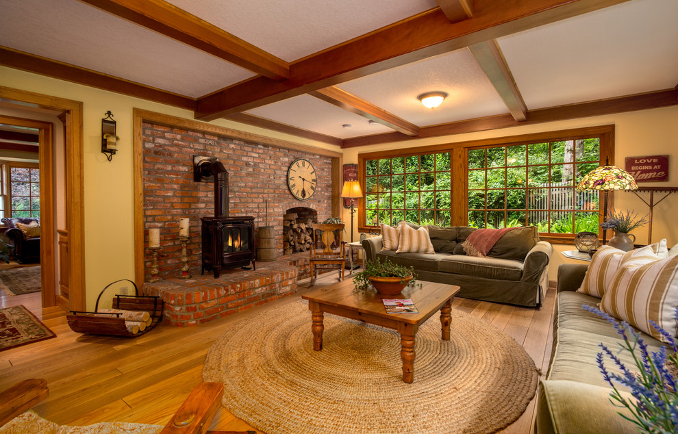 Design ideas for a large farmhouse enclosed games room in Seattle with yellow walls, medium hardwood flooring, a wood burning stove and a brick fireplace surround.