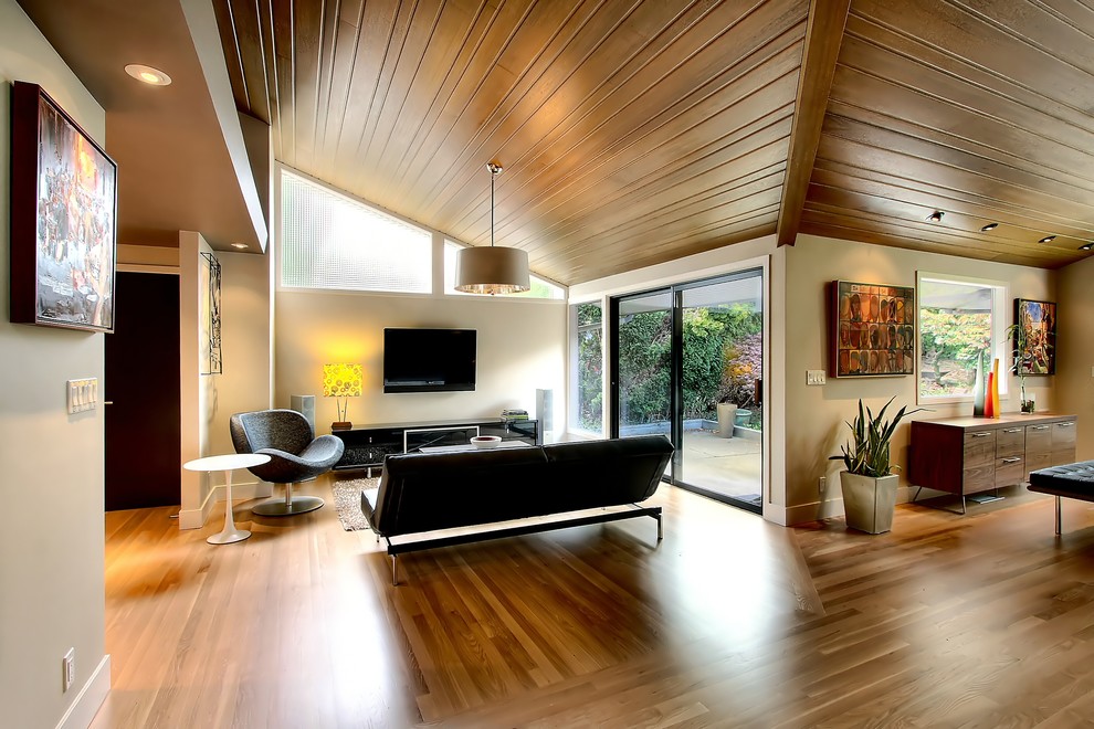 Offenes Modernes Wohnzimmer mit beiger Wandfarbe, braunem Holzboden und TV-Wand in Seattle