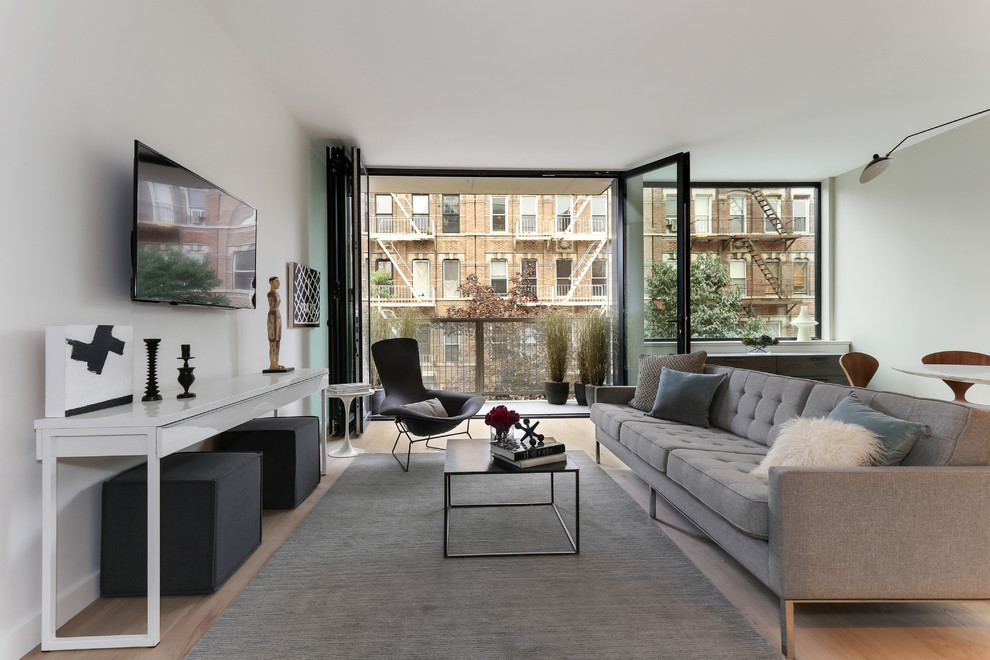 Offenes Modernes Wohnzimmer mit weißer Wandfarbe, hellem Holzboden und TV-Wand in New York