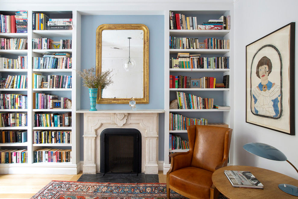 Immagine di un soggiorno chic con libreria, pareti blu, parquet chiaro, camino classico e pavimento marrone