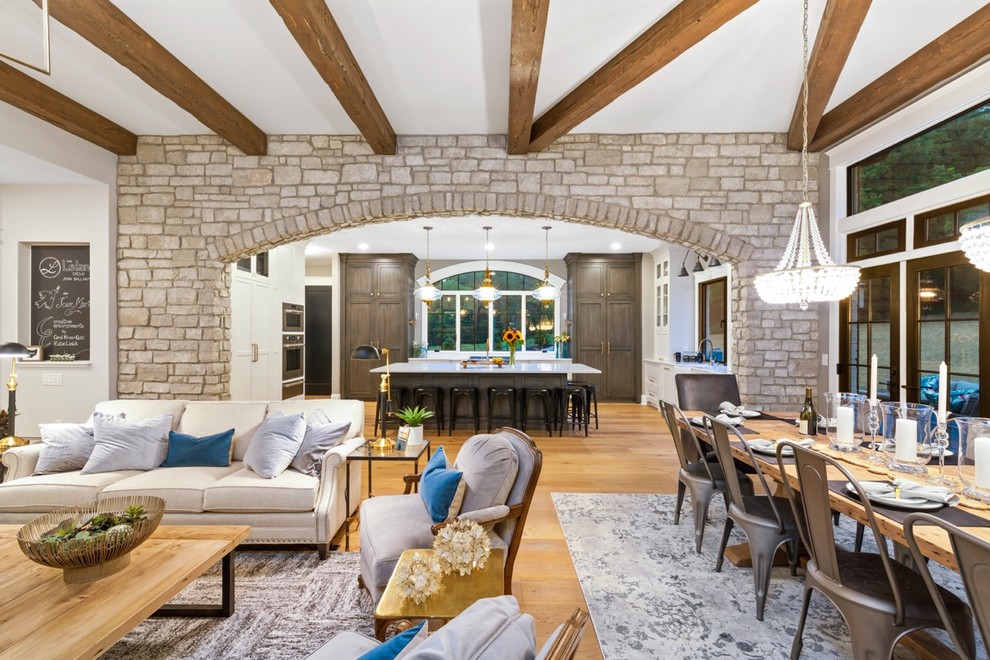 Ejemplo de sala de estar abierta clásica renovada de tamaño medio con paredes grises, suelo de madera en tonos medios, todas las chimeneas y marco de chimenea de piedra
