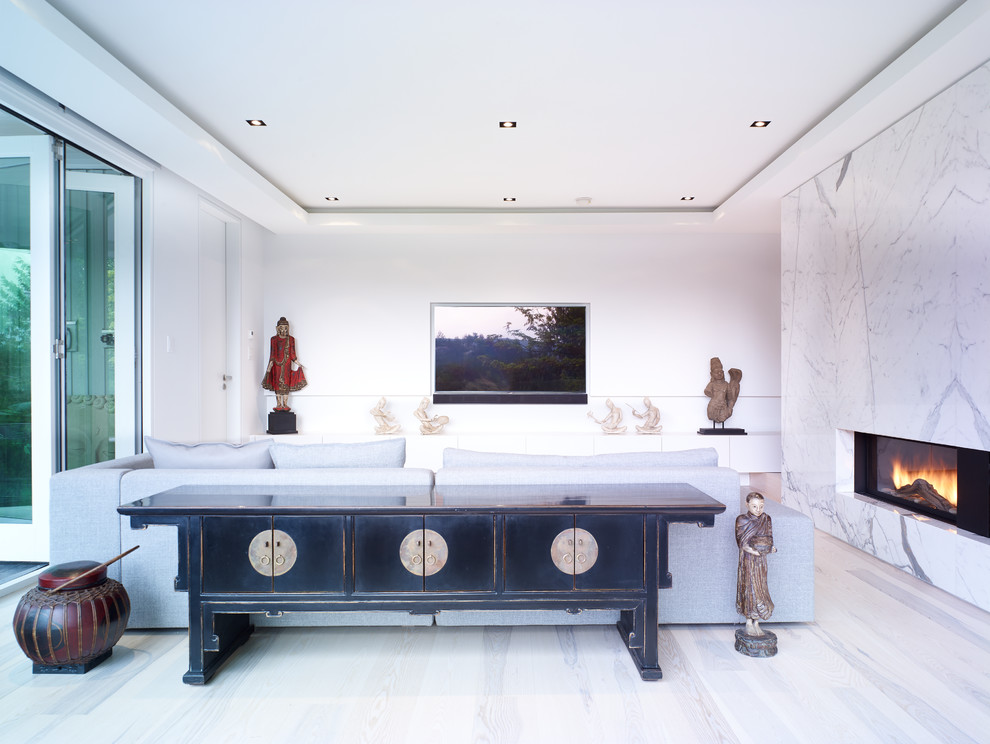 バンクーバーにある高級な中くらいなアジアンスタイルのおしゃれな独立型ファミリールーム (白い壁、淡色無垢フローリング、横長型暖炉、石材の暖炉まわり、埋込式メディアウォール、ベージュの床) の写真