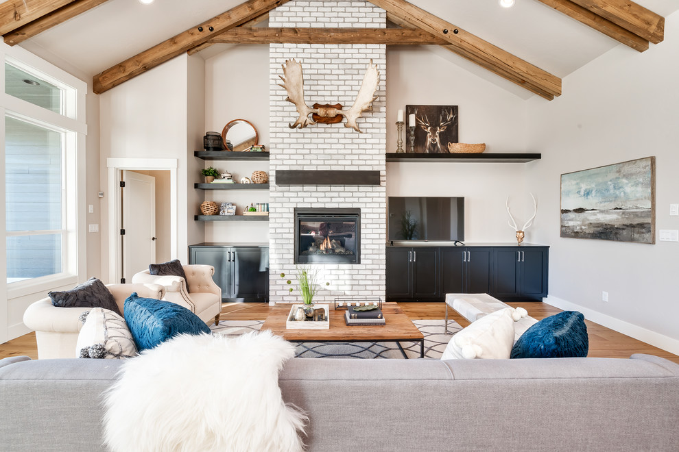 Abgetrenntes Klassisches Wohnzimmer mit beiger Wandfarbe, braunem Holzboden, Kamin, Kaminumrandung aus Backstein und freistehendem TV in Boise
