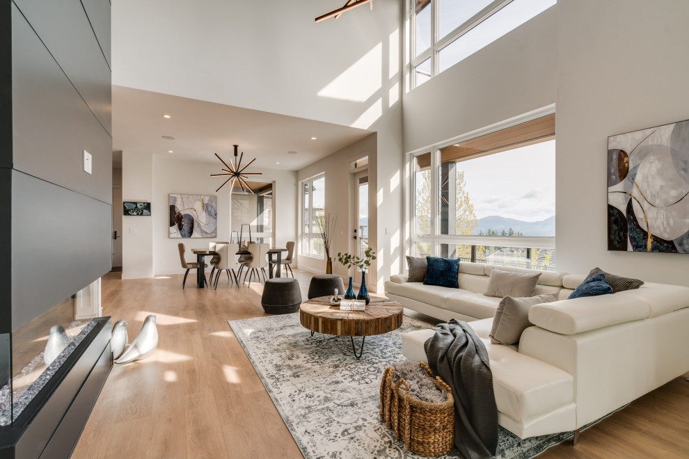 Large trendy open concept laminate floor and brown floor family room photo in Vancouver with white walls, a two-sided fireplace, a shiplap fireplace and a wall-mounted tv