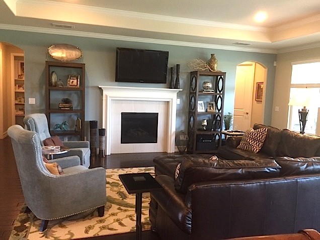 Cette image montre une salle de séjour traditionnelle de taille moyenne et ouverte avec un mur bleu, parquet foncé, cheminée suspendue, un manteau de cheminée en bois, un téléviseur fixé au mur et un sol marron.