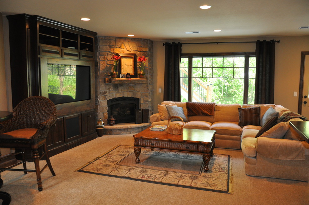Modelo de sala de estar abierta clásica grande con paredes beige, moqueta, chimenea de esquina, marco de chimenea de piedra y pared multimedia