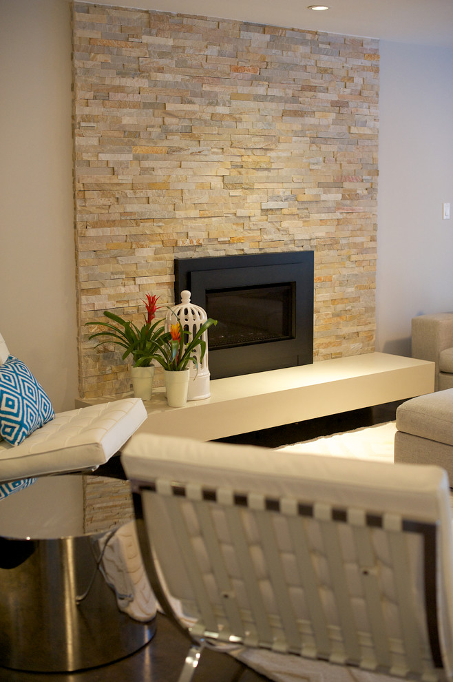 Imagen de sala de estar contemporánea grande con paredes grises, suelo de madera oscura, marco de chimenea de piedra, televisor colgado en la pared y chimenea lineal