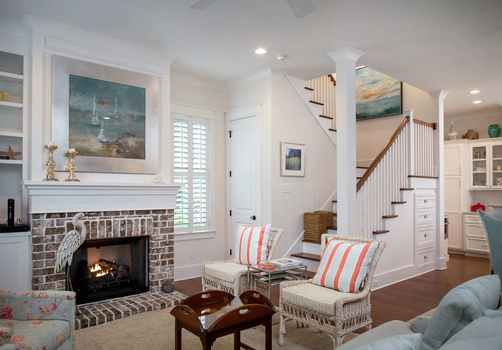 Mittelgroßes, Offenes Maritimes Wohnzimmer mit weißer Wandfarbe, Kamin, Kaminumrandung aus Backstein und braunem Holzboden in Charleston
