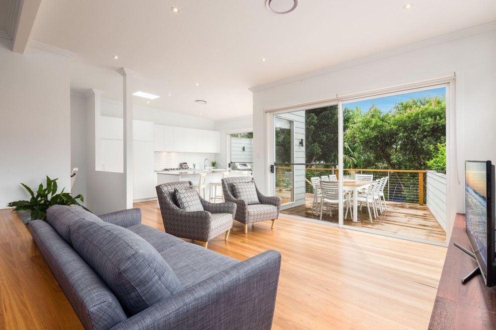 Mittelgroßes, Offenes Modernes Wohnzimmer mit weißer Wandfarbe, braunem Holzboden und freistehendem TV in Sydney