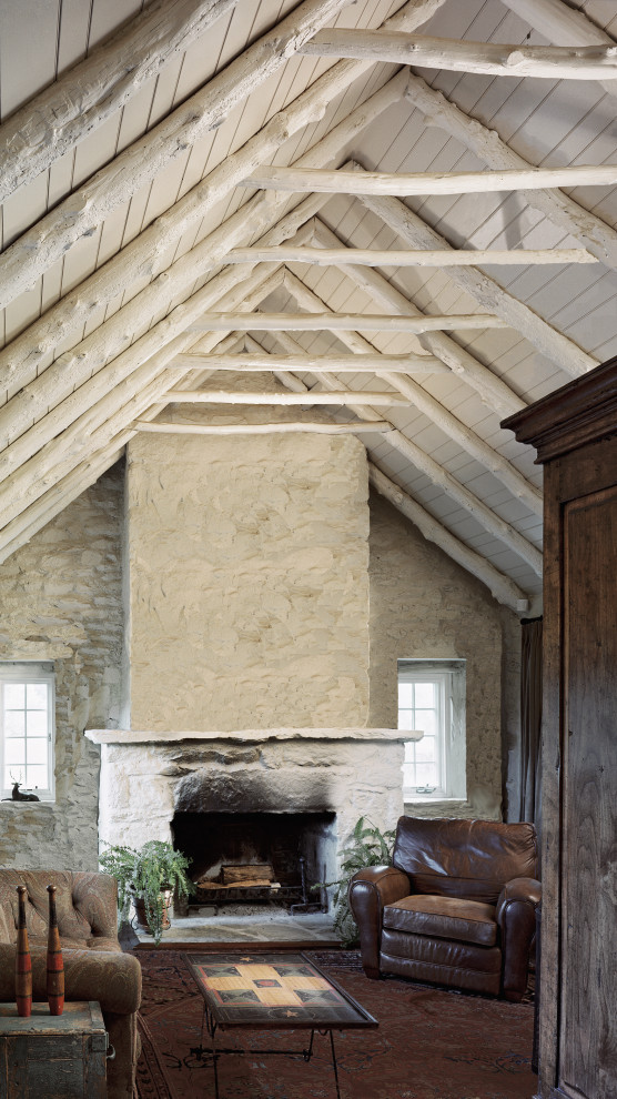 Exemple d'une salle de séjour nature de taille moyenne et fermée avec un mur blanc, un sol en ardoise, une cheminée standard et un manteau de cheminée en pierre.