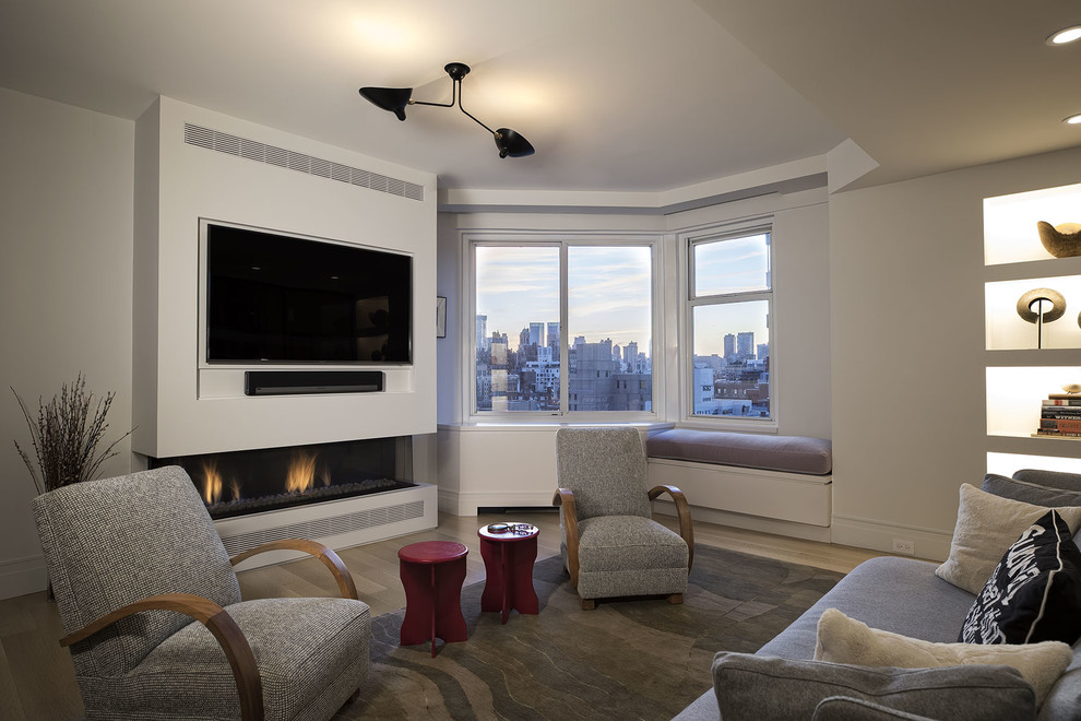 На фото: изолированная гостиная комната среднего размера в стиле неоклассика (современная классика) с белыми стенами, светлым паркетным полом, горизонтальным камином, фасадом камина из штукатурки и телевизором на стене