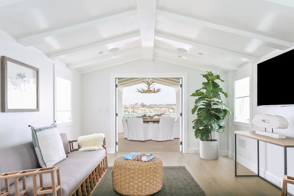 Пример оригинального дизайна: гостиная комната в морском стиле с белыми стенами, светлым паркетным полом и телевизором на стене