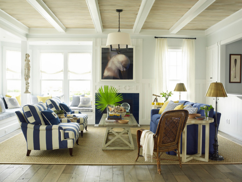 Cette image montre une grande salle de séjour mansardée ou avec mezzanine marine avec un mur bleu, une cheminée standard et un manteau de cheminée en carrelage.
