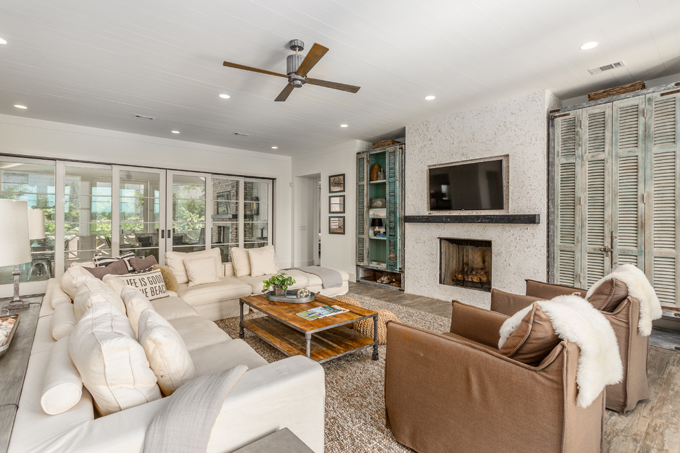 Photo of a beach style enclosed living room in Jacksonville with beige walls, a standard fireplace, a wall mounted tv and brown floors.