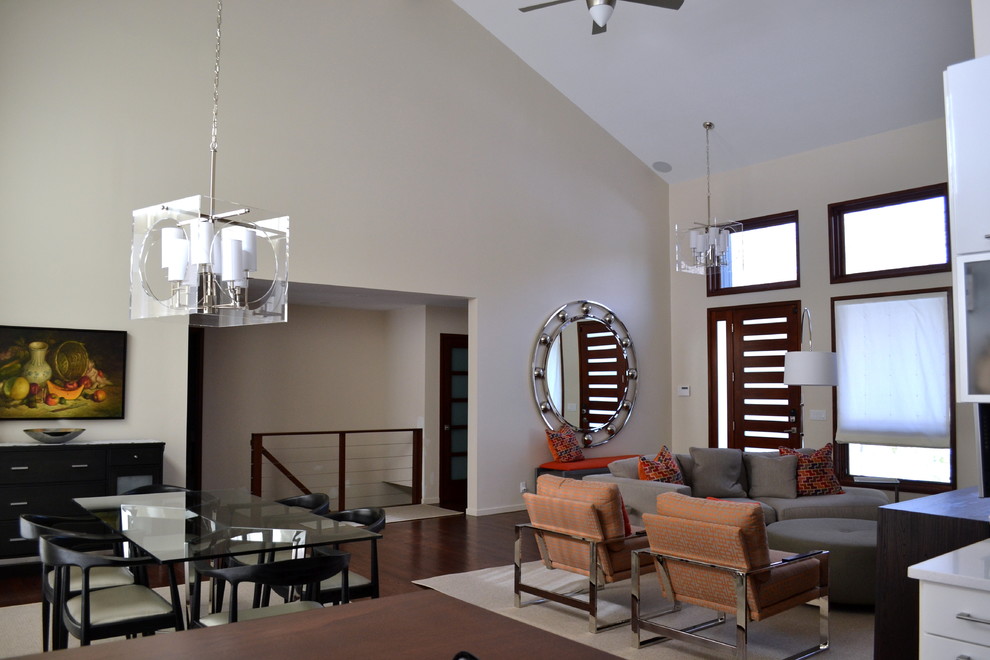 Imagen de sala de estar abierta contemporánea grande con paredes beige, suelo de madera oscura, todas las chimeneas, marco de chimenea de ladrillo y televisor colgado en la pared