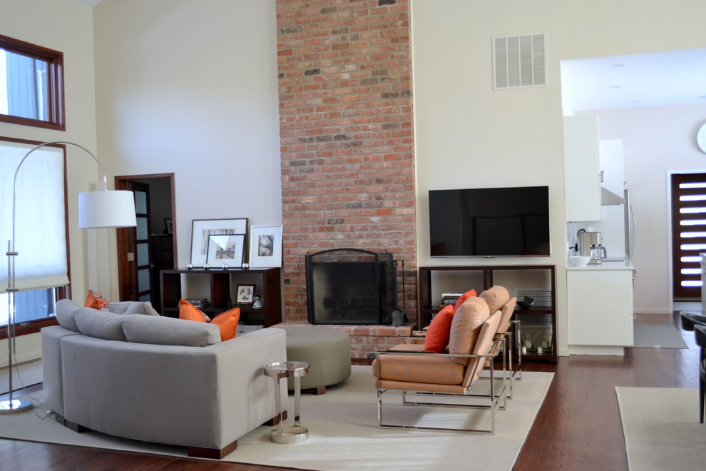 Example of a large trendy open concept dark wood floor family room design in New York with beige walls, a standard fireplace, a brick fireplace and a wall-mounted tv
