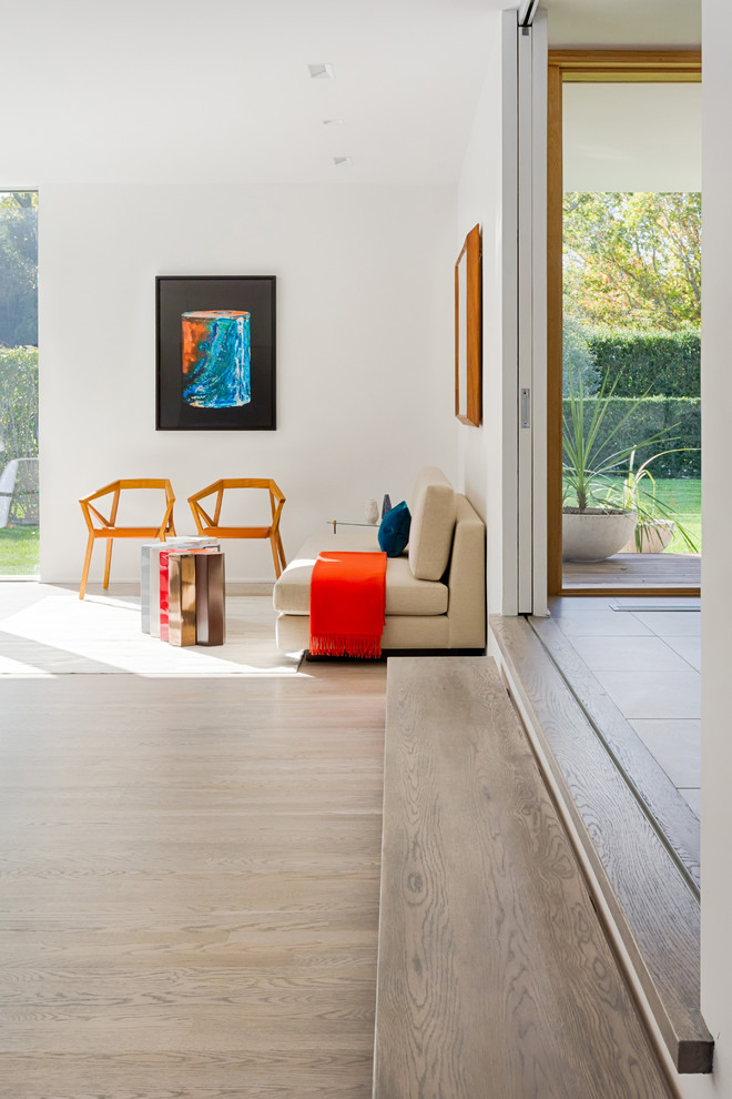 Mid-sized trendy open concept light wood floor family room photo in Charleston with white walls