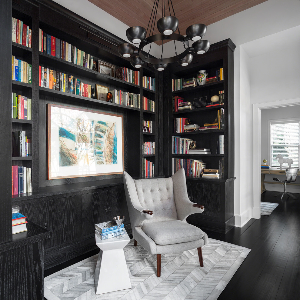 Cette photo montre une salle de séjour chic ouverte avec une bibliothèque ou un coin lecture, un mur blanc, aucune cheminée et un sol noir.