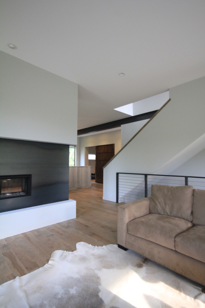 Идея дизайна: открытая гостиная комната среднего размера в стиле модернизм с белыми стенами, полом из бамбука, двусторонним камином, фасадом камина из металла и скрытым телевизором