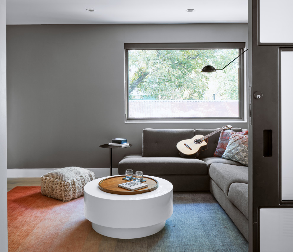 Ejemplo de sala de estar cerrada contemporánea grande con paredes grises, suelo de madera clara y suelo beige