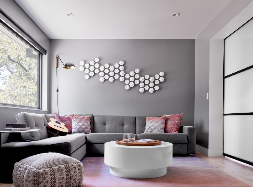 Aménagement d'une salle de séjour contemporaine ouverte avec un mur gris et parquet clair.