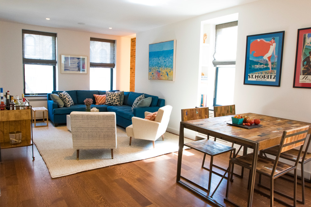 Modelo de sala de estar tipo loft minimalista pequeña con paredes blancas, suelo de madera en tonos medios, televisor colgado en la pared y alfombra