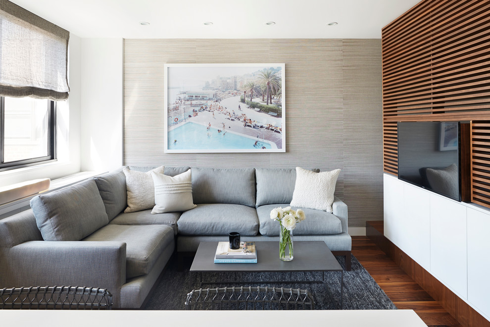 Imagen de sala de estar abierta actual con paredes blancas, suelo de madera en tonos medios y televisor colgado en la pared