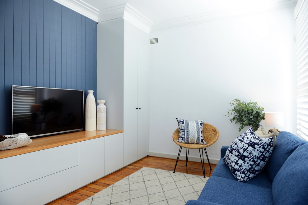 Idée de décoration pour une salle de séjour design de taille moyenne et fermée avec un mur bleu et un téléviseur fixé au mur.
