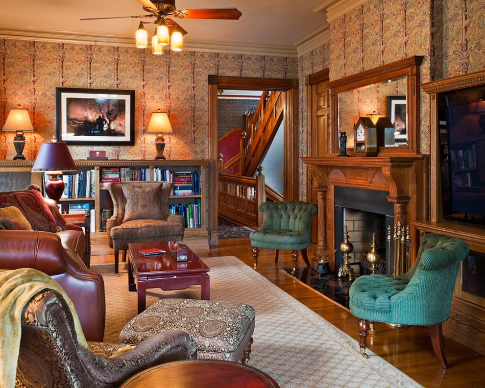 Cette image montre une salle de séjour traditionnelle avec une bibliothèque ou un coin lecture, un mur beige, un sol en bois brun, une cheminée standard et un manteau de cheminée en bois.