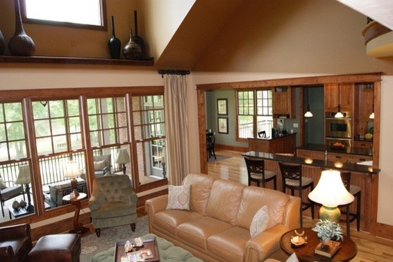 Aménagement d'une salle de séjour craftsman de taille moyenne et ouverte avec un mur beige, un sol en bois brun, une cheminée standard, un manteau de cheminée en pierre et un téléviseur encastré.