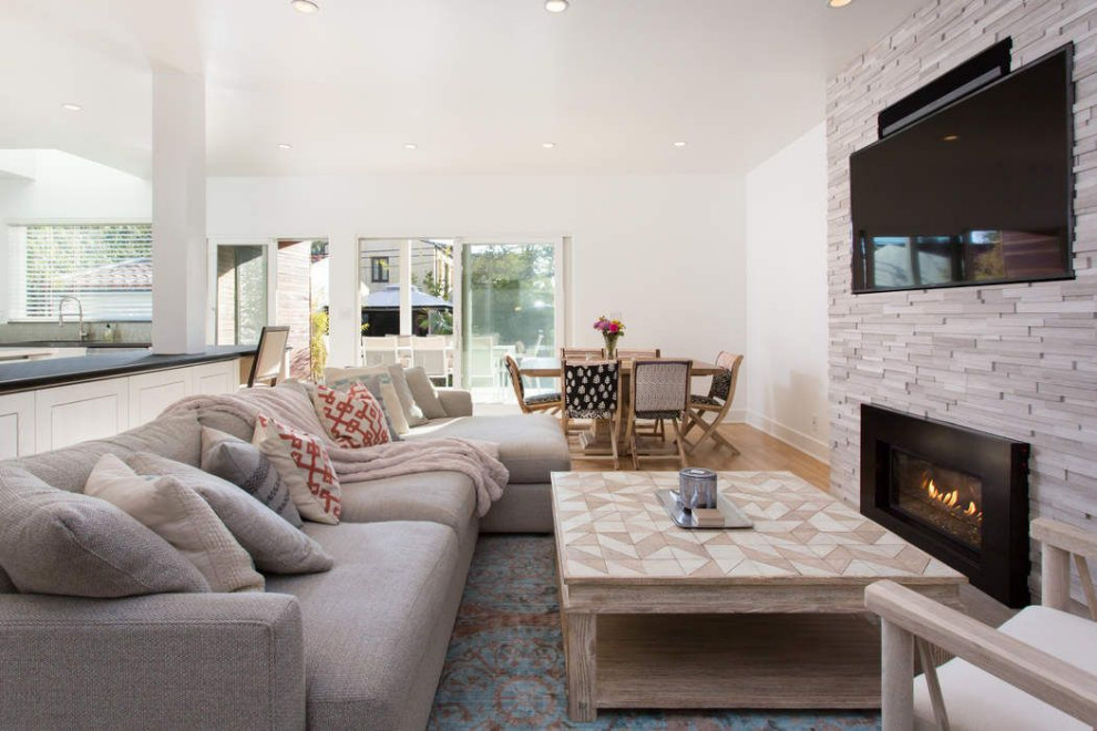 Großes, Offenes Eklektisches Wohnzimmer mit weißer Wandfarbe, hellem Holzboden, Gaskamin, Kaminumrandung aus gestapelten Steinen, TV-Wand und beigem Boden in Los Angeles