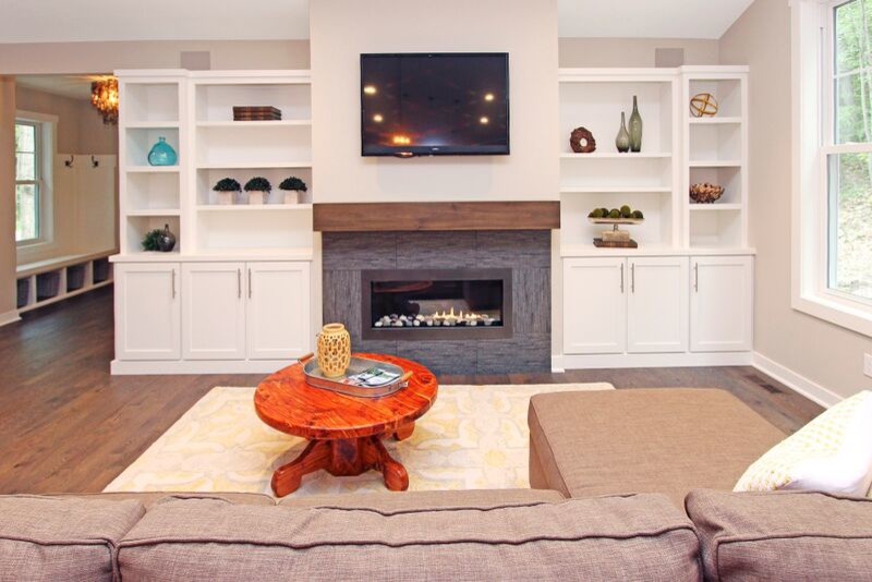 Example of an eclectic medium tone wood floor family room design in Grand Rapids with a ribbon fireplace, a tile fireplace and a wall-mounted tv