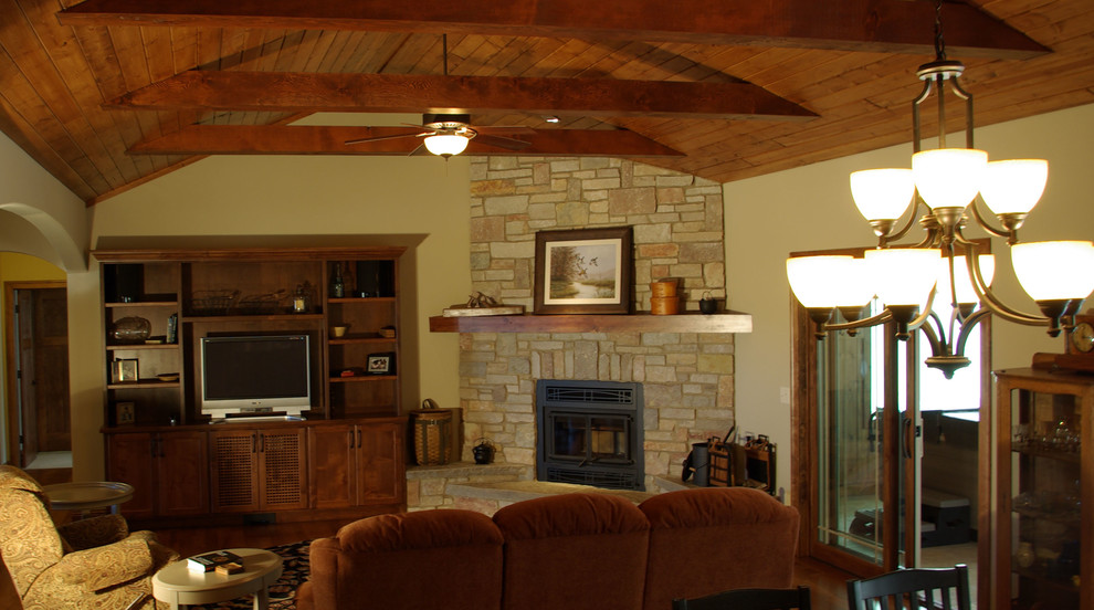 Imagen de sala de estar abierta tradicional de tamaño medio con paredes amarillas, suelo de madera en tonos medios, todas las chimeneas, marco de chimenea de piedra y pared multimedia