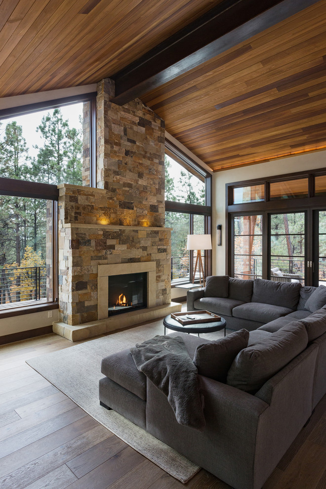 Inspiration for a rustic dark wood floor family room remodel in Albuquerque with beige walls, a standard fireplace, a stone fireplace and no tv