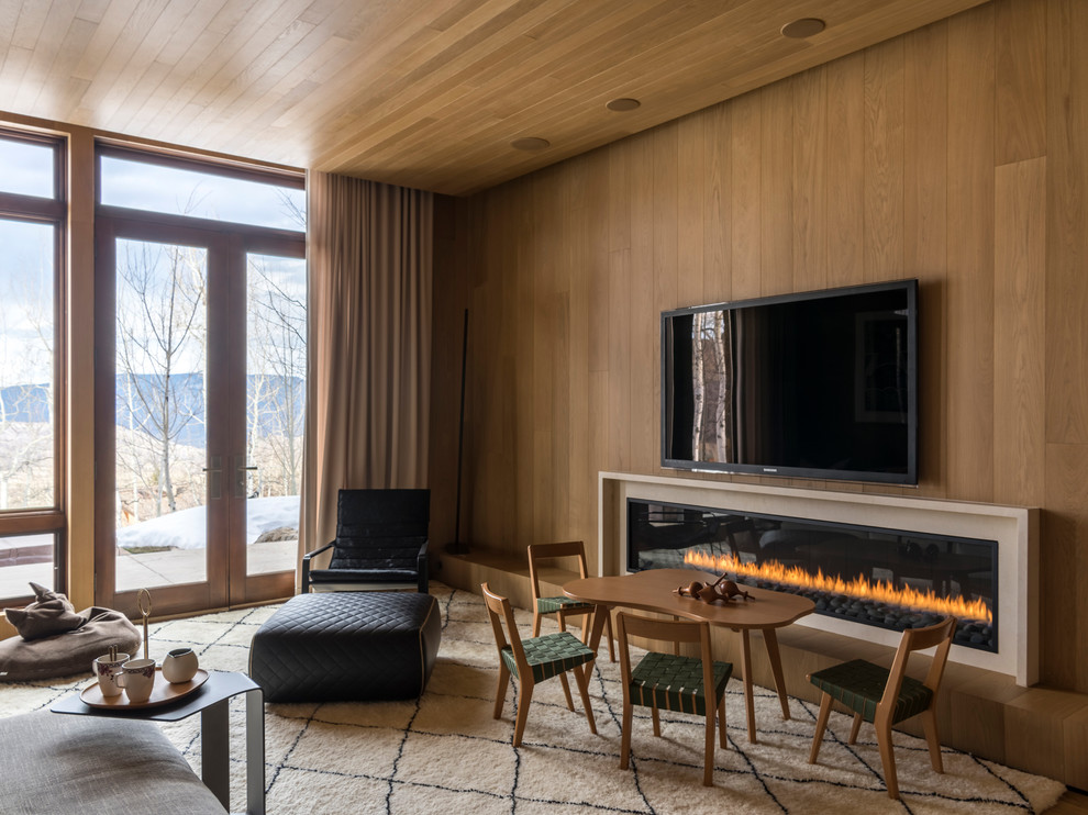 Ejemplo de sala de estar abierta contemporánea grande con suelo de madera en tonos medios, chimenea lineal, marco de chimenea de piedra, televisor colgado en la pared, paredes marrones y suelo marrón