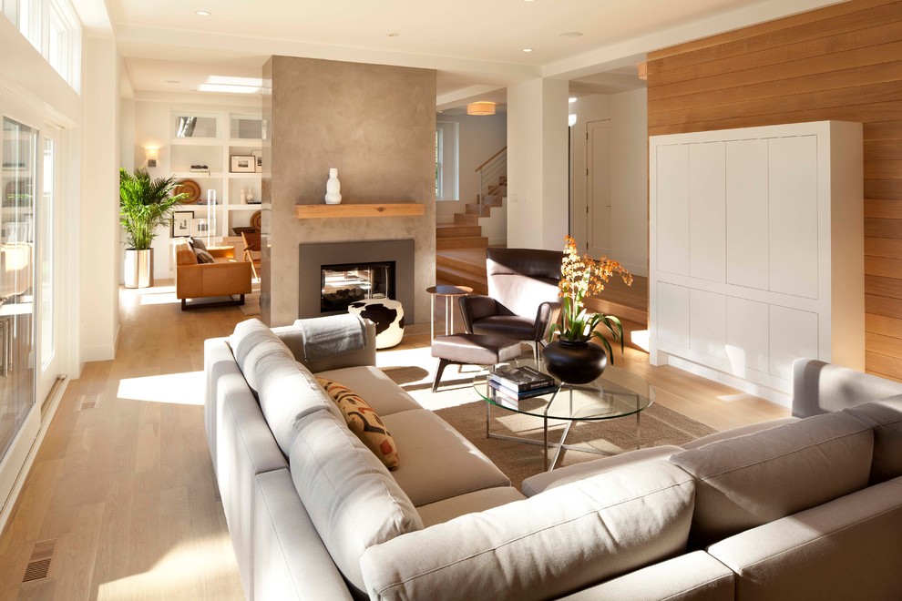 Стильный дизайн: открытая гостиная комната в современном стиле с светлым паркетным полом, двусторонним камином и ковром на полу - последний тренд