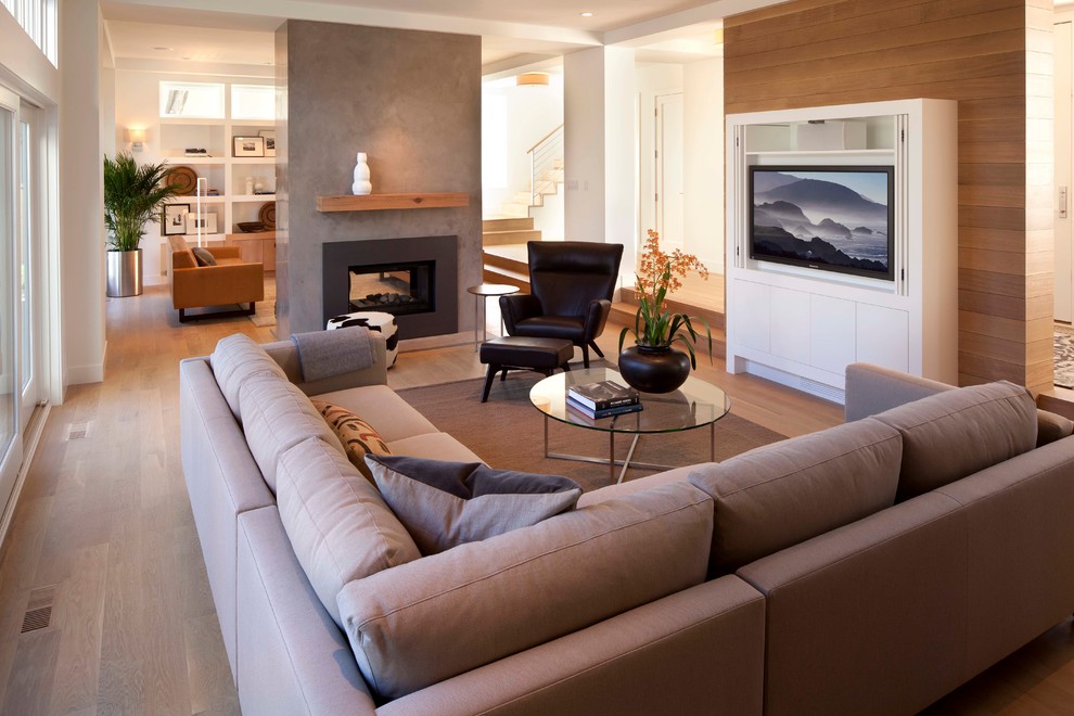 Diseño de salón abierto actual con suelo de madera en tonos medios, chimenea de doble cara, pared multimedia y alfombra