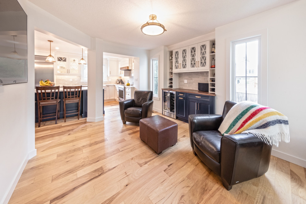 Mittelgroßes, Offenes Rustikales Wohnzimmer mit Hausbar, weißer Wandfarbe, braunem Holzboden, TV-Wand und braunem Boden in Edmonton