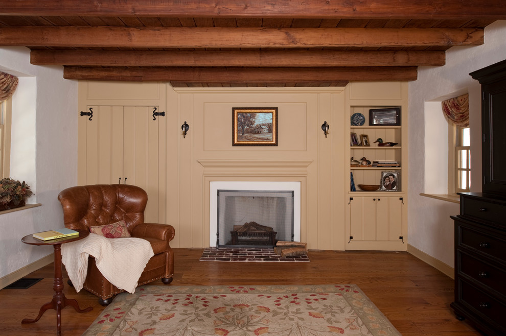 Exemple d'une salle de séjour nature fermée avec un mur blanc, un sol en bois brun, une cheminée standard et un manteau de cheminée en bois.