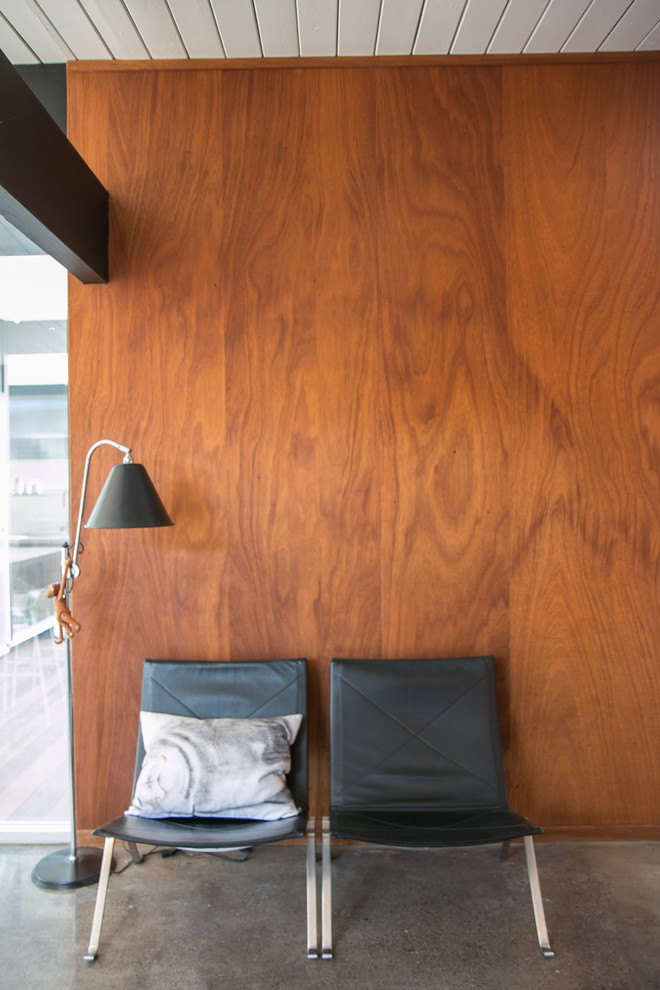 Esempio di un piccolo soggiorno minimalista aperto con pareti marroni e pavimento in cemento